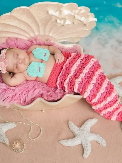 A wider view of the 'Baby Mermaid' setup, showing the seashell prop on a sandy shore with starfish, creating a complete and magical underwater world.