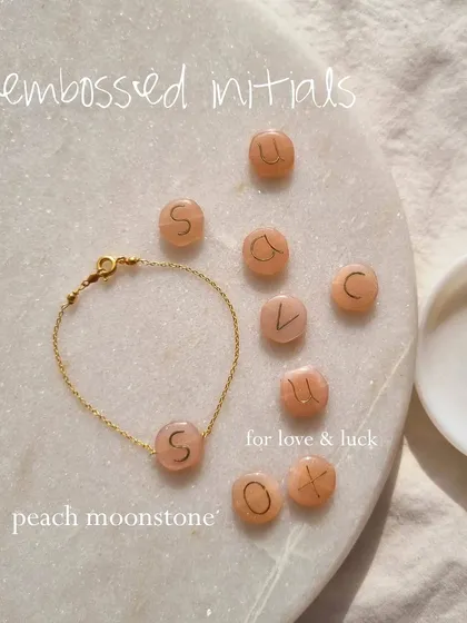 I love creating pieces that are deeply personal. Here you can see how I hand-emboss initials onto a pebble-shaped Peach Moonstone, a stone known for attracting abundance and good fortune in love. It makes for a truly meaningful gift.