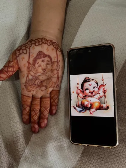This image shows the reference photo next to my henna recreation of a baby Ganesha, demonstrating my ability to accurately replicate images in my art.