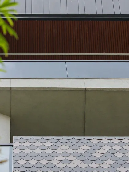 A detail of the Akashneem Marg facade, showing the contrast between the smooth concrete, wood-look ceiling, and the decorative fish-scale tiles.