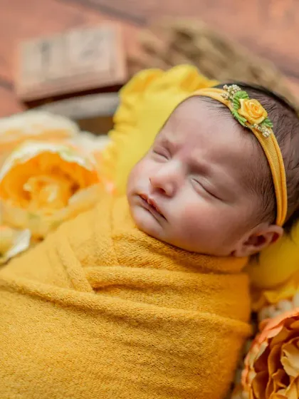 A tight close-up on the baby's face, capturing their peaceful expression and the texture of the yellow wrap.