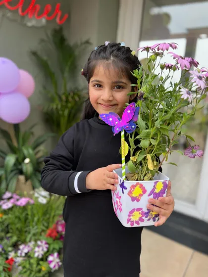 The best part of art is seeing the final creation. This young artist is proudly showing off her hand-painted flower pot, now a beautiful home for a real plant.