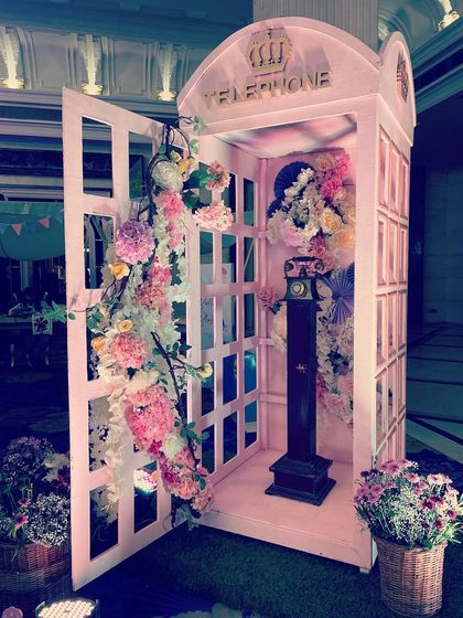 A beautiful pink telephone booth overflowing with flowers, a classic and romantic photo opportunity for a Parisian-themed event.