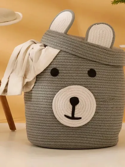 Here is the bear storage basket in a lovely grey color, shown holding a piece of clothing to demonstrate its use as a laundry hamper.