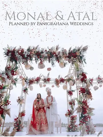 A breathtaking rooftop mandap with a rustic-glam design, using pampas grass and deep red florals against a cloudy sky for a dramatic effect.
