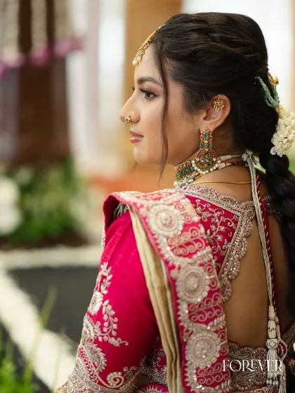 A profile shot that details the elegant updo with fresh jasmine flowers and the intricate blouse design.