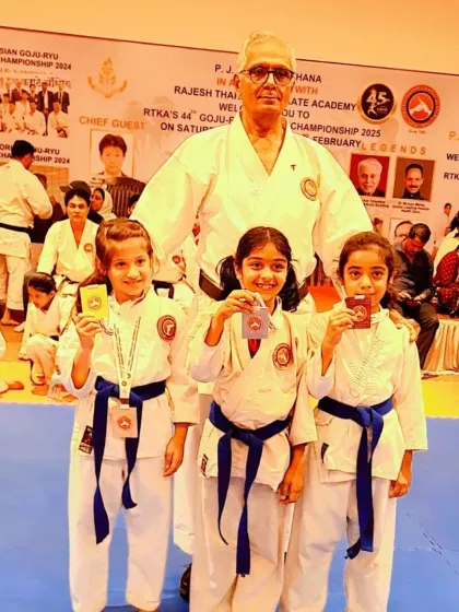 Three of our young female students show off their medals with Kyoshi Sensei. We encourage and celebrate the achievements of all our karatekas, fostering a sense of accomplishment.