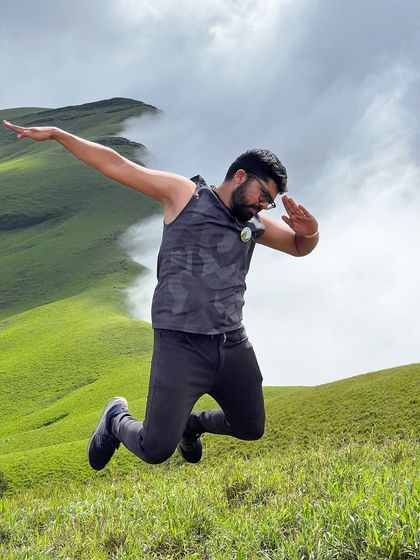 That feeling of accomplishment. A trekker jumps for joy against the stunning backdrop of the Netravathi hills.