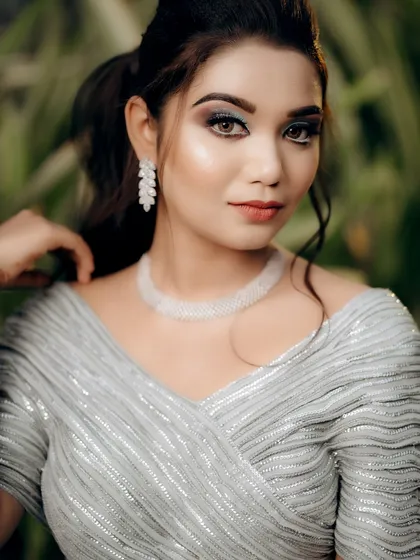 A beautiful close-up bridal portrait. The focus is on her flawless makeup and the intricate details of her jewelry and shimmering top.