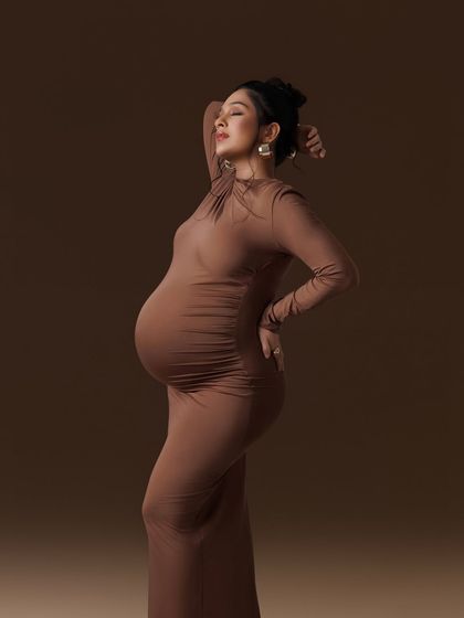 An elegant and powerful pose in a form-fitting brown gown, highlighting the beautiful curves of pregnancy.