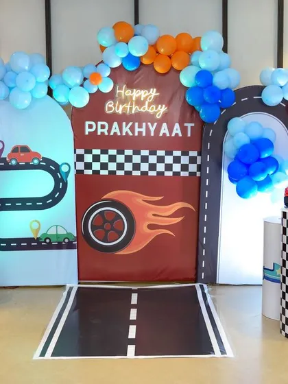 A vibrant, car-themed fifth birthday party setup, complete with a racetrack, traffic lights, and colorful balloons. We enjoy capturing the energy and creativity of themed parties for kids of all ages.