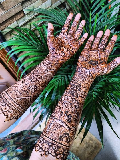 Another angle of Safeena's engagement henna, set against a background of green leaves which makes the brown paste stand out.