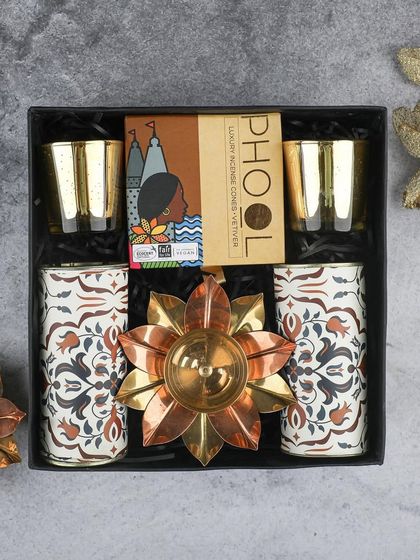 The "Divine" Diwali hamper, featuring elegant brass T-light holders, Phool incense, and other festive decor items in a sleek black gift box.