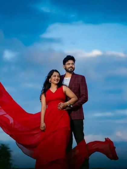 A beautiful couple's portrait against a dramatic sky. The red flying gown and the partner's blazer create a look that is both elegant and modern.