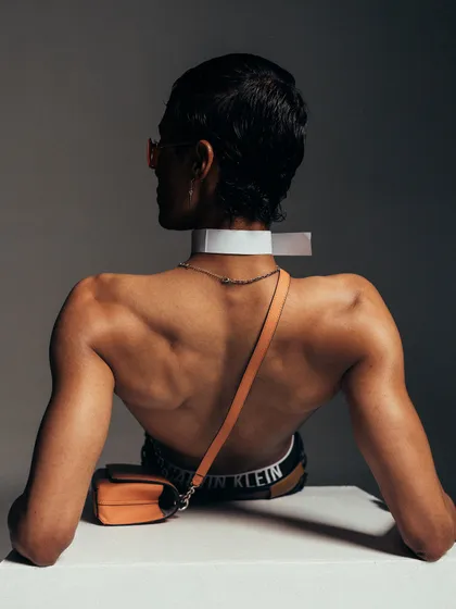 A wider shot from the back, providing more context to the pose and styling. The composition is strong and architectural, emphasizing the model's form.