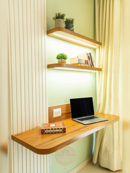 A chic guest bedroom with a pastel green accent wall and a custom floating study desk with integrated lighting.