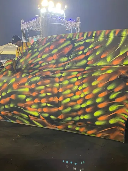A side view of the custom-painted MINI. The pattern of bright orange and yellow spray dots creates a sense of speed and energy, completely changing the look of the car.