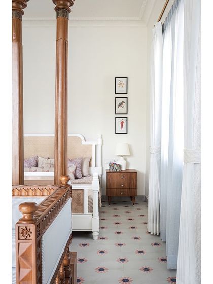 The daughter's bedroom combines elegance and simplicity, with a beautiful white four-poster bed and custom cement tiles that add a soft touch of color.