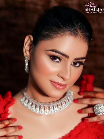 A stunning look for an evening event. The client is wearing a beautiful red dress with a statement diamond necklace, and her makeup is bold and glamorous.