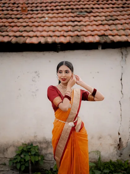 A serene portrait of a model in a traditional saree. The composition against a rustic wall creates a timeless and elegant feel, perfect for showcasing ethnic wear.