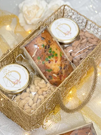 Here you can see the contents of my large mesh basket hamper for Diwali. It includes two different tea cakes, jars of salted cashews and almonds, and two dessert jars, offering a wonderful variety of sweet and savory treats.