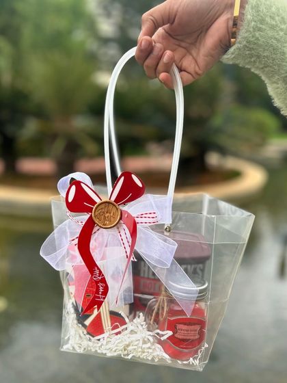 A cute and festive Rakhi hamper in a clear bag. The red-themed goodies and the custom wax-sealed bow make it a sweet and simple gift.