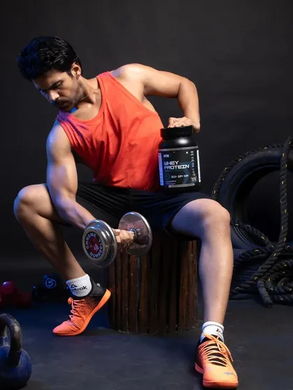 This image captures a male model in a classic workout pose, highlighting muscle definition while holding the whey protein container. It’s a perfect visual for marketing materials targeting bodybuilders and serious gym-goers, combining aspirational fitness with clear product placement.