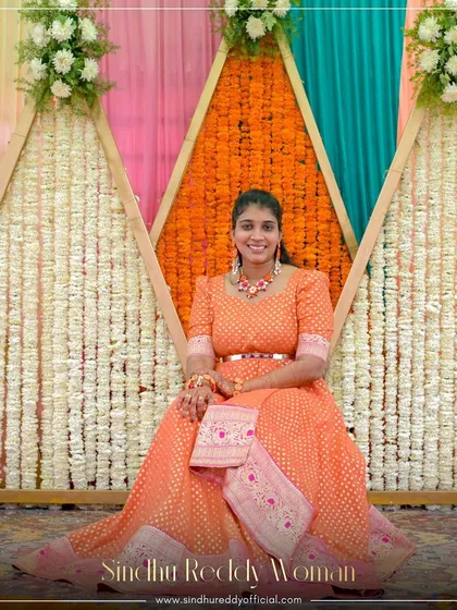 A client looking radiant in a custom orange Banarasi gown, perfect for a festive celebration.