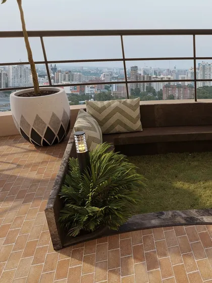 Details like the chevron-patterned cushions and small accent plants add layers of texture and interest to the balcony design.