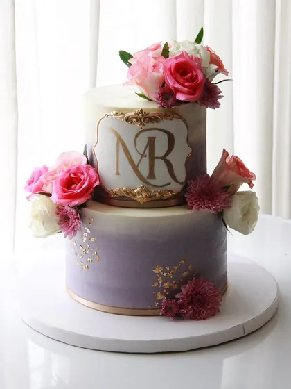 An engagement cake in a lovely lavender ombre, accented with gold leaf and fresh pink and white roses.