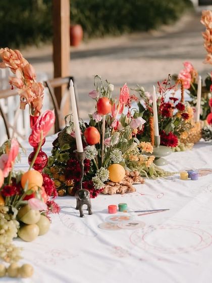 A long table runner of tropical flowers and fruits, creating a vibrant and abundant centerpiece for the beachside dinner.