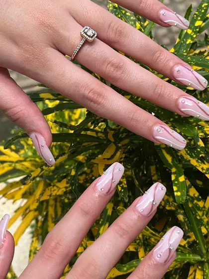 Swirling into a world of color and sparkle. This intricate design on long, coffin-shaped extensions features delicate swirls, dotted with tiny pearls and rhinestones for a truly luxurious finish.