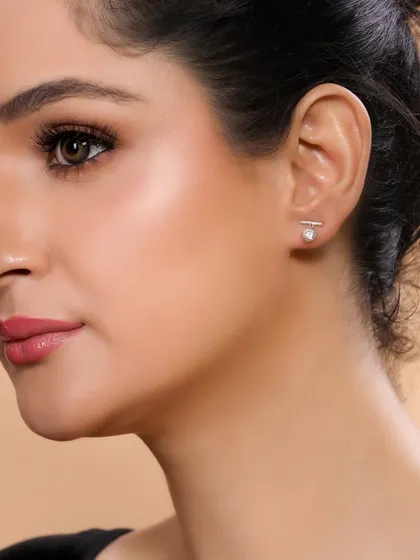 A close-up of a model wearing minimalist stud earrings. This type of clean, simple shot is essential for any e-commerce store selling fine jewellery.