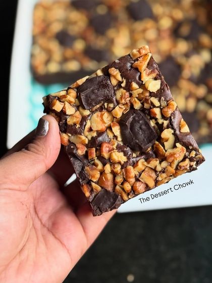 A single piece of my walnut brownie held up to the camera. It's the perfect bite-sized treat, packed with flavor and texture.