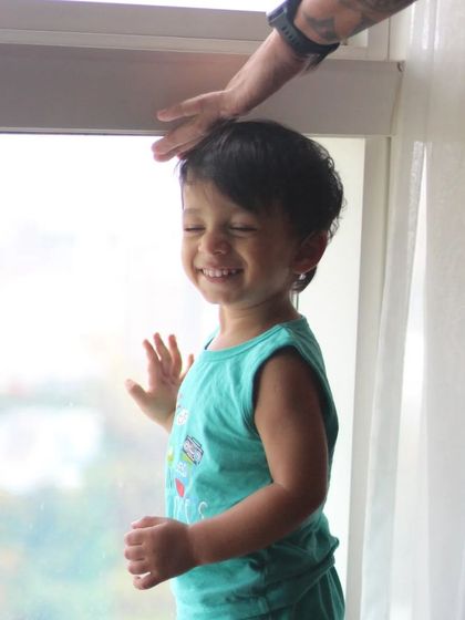 A happy moment before the first trim. Building trust with my youngest clients is key. I make sure they feel at ease before I even pick up the clippers, ensuring a positive barbershop experience from the start.