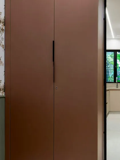 This custom wardrobe was designed for a multi-functional nap room. The clean, handleless design in a warm brown finish complements the room's cozy aesthetic while providing essential storage.
