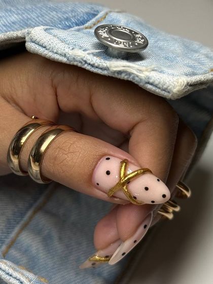 A close-up showing how the sculpted gold nail art element seamlessly integrates with the client's own rings, creating a cohesive and high-fashion look.