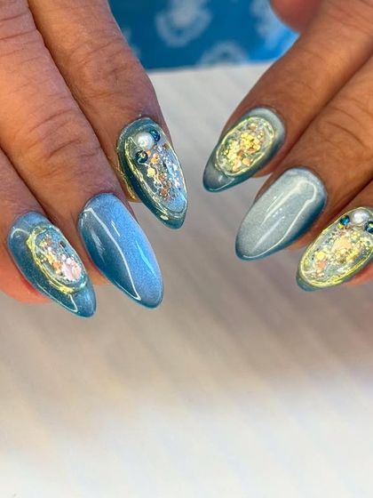 This unique design features a mesmerizing blue cat-eye base with encapsulated glitter and pearls. It creates a stunning, galaxy-like effect on the nails.