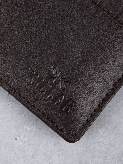 A close-up of the embossed logo on a dark brown leather wallet.