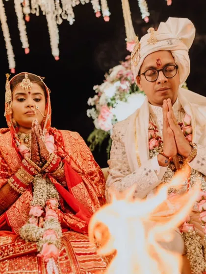 A solemn moment of prayer during a Hindu wedding ceremony, with the sacred fire in the foreground.