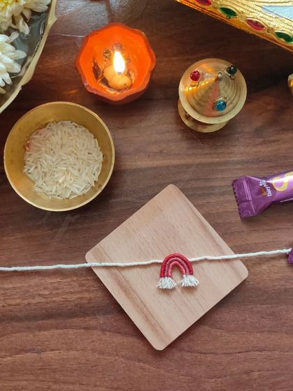 A cute and simple handmade rakhi featuring a small embroidered rainbow. This is a unique design perfect for celebrating the bond of siblings.