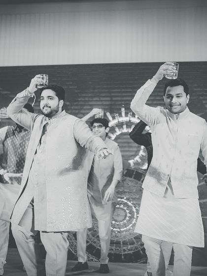 A black and white shot of the groom's crew raising a glass during their performance. We choreograph fun, thematic routines.