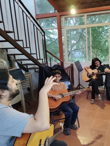 A glimpse into a typical day at our studio. Here, one of our instructors guides students during a group guitar lesson. We focus on creating a supportive environment where students can learn from both teachers and peers.