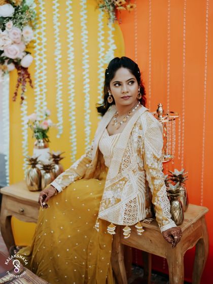 A stylish portrait of the bride at her carnival-themed event, posing against a vibrant orange backdrop.
