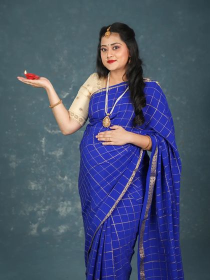 A portrait of grace. The mom-to-be holds a diya, symbolizing light and hope, while dressed in a beautiful blue saree for her traditional maternity photoshoot.