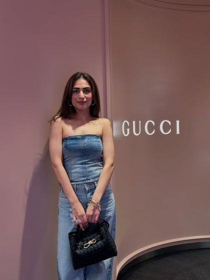 A closer look at the denim outfit, highlighting the black handbag that completes the ensemble.