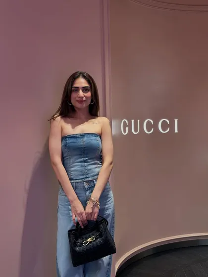 A closer look at the denim outfit, highlighting the black handbag that completes the ensemble.
