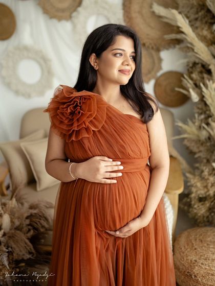 Looking towards the future with a happy glow. This portrait captures the hopeful and joyful spirit of pregnancy, with the warm tones of the gown adding to the beautiful mood.