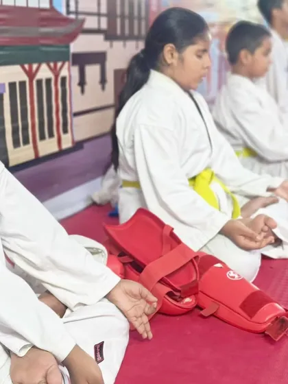 Even with their gear nearby, students take the time to meditate. This teaches them to find stillness and focus even in a training environment.