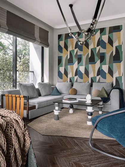 A more casual seating area features a bold geometric wall tapestry and a mix of contemporary furniture, showcasing a different mood within the same home.